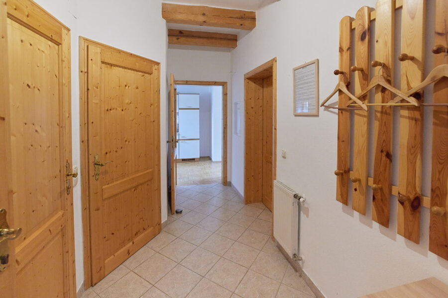 Hier sieht mann einen hellen großzügigen Flur mit Türen aus Holz und einer Gaderobe