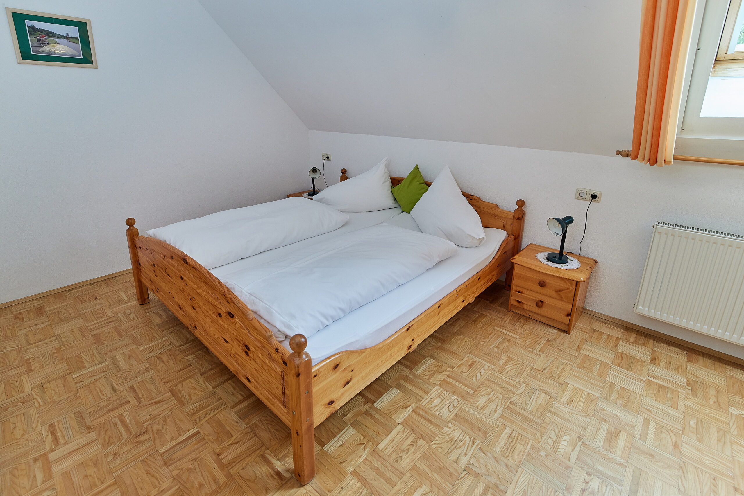 Helles Doppelbettzimmer mit Parkettboden und Sicht zur Westseite.