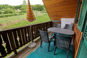 Der geräumige Balkon verfügt über eine große Sitzgarnitur. Der Blick geht über eine Johanisbeerkultur zum entfernten Nachbarhaus. auf der anderen Seite vom Balkon befinden sich die Liegestühle.